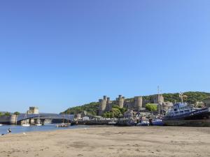 a beach with a bridge and a castle in the background at Millgate Cottage in Conwy