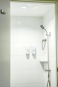 a shower in a bathroom with white tiles at PICCOLO SUKHUMVIT HOSTEL in Bangkok