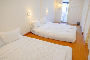2 camas blancas en una habitación con suelo de madera en PICCOLO SUKHUMVIT HOSTEL, en Bangkok