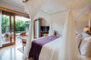 ケラマスにあるDesa Swan Villas & SPA, Keramasのベッドルーム(天蓋付き白いベッド1台付)