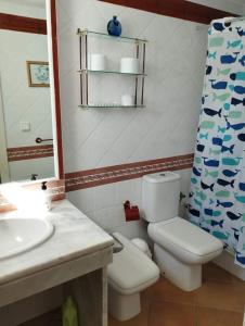 ein Badezimmer mit einem WC, einem Waschbecken und einem Spiegel in der Unterkunft La Casita de Marina Golf-Costa Ballena in Cádiz