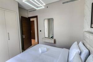 een slaapkamer met een wit bed en een spiegel bij STAY BY LATINEM Luxury 1BR Holiday Home CVR B3102 near Burj Khalifa in Dubai