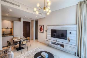 een woonkamer met een grote televisie en een tafel bij STAY BY LATINEM Luxury 1BR Holiday Home CVR B3102 near Burj Khalifa in Dubai