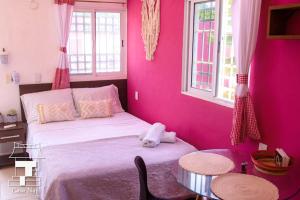 Schlafzimmer mit rosa Wänden und einem Bett mit einem Tisch in der Unterkunft Najil House St1 in Bacalar