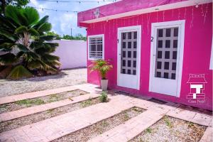 a pink house with white doors and a palm tree at Najil House St1 in Bacalar