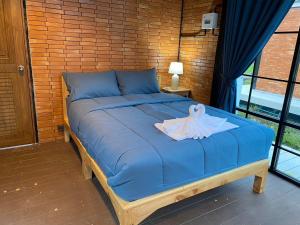 a blue bed with a robe on top of it at The Maewin Coffee & Cottage Economy Double Room in Ban Huai Rin