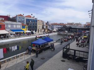 a group of people walking along a river with buildings at Flamingo's House - Beautiful View Over the Canal in Aveiro