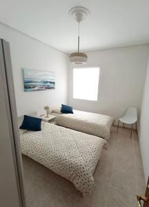 a room with two beds and a table and a chair at Apartamento BERO in Santoña