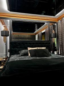 Schlafzimmer mit einem schwarzen Bett und einem schwarzen Kopfteil in der Unterkunft LuxuryApartments in Warschau