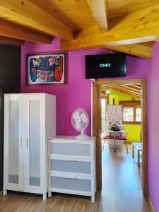 Cette chambre est dotée d'un mur violet et d'une commode blanche. dans l'établissement Tranquila casita de invitados en Vigo con chimenea, à Vigo