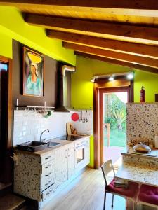 a kitchen with yellow walls and a table with a sink at Tranquila casita de invitados en Vigo con chimenea in Vigo