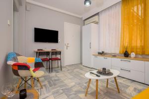 een woonkamer met een televisie en een tafel en stoelen bij 148 CENTRAL STUDIO AXD in Alexandroupoli