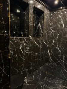 baño con paredes de mármol negro y espejo en LuxuryApartments, en Varsovia