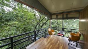 Habitación con 2 sillas y balcón con árboles. en Ambassador Hotel, en Suncheon