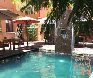 a swimming pool with an umbrella and a table and chairs at Hotel Sakamanga in Antananarivo