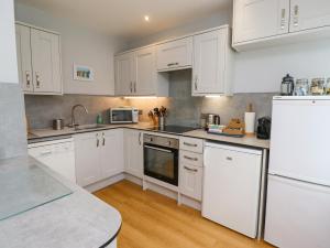 a kitchen with white cabinets and white appliances at Manor Cottage in Embleton +10 photos