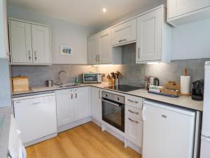 a white kitchen with white cabinets and a microwave at Manor Cottage in Embleton