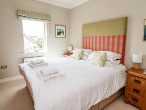 a bedroom with a large white bed with a window at Cuddy's Holm in Seahouses