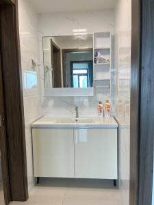 une salle de bain blanche avec un lavabo et un miroir dans l'établissement Forest city Ataraxia park homestay, à Johor Bahru