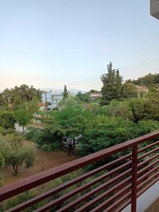 un balcone con una recinzione rossa e alberi di LOVELY APARTMENT a PalaiónTsiflíkion