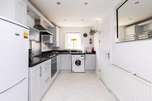 a kitchen with white cabinets and a washer and dryer at Coastal Retreat in Carmarthenshire in Llanelli