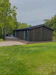 un edificio de madera con un campo de césped delante de él en Island House atostogų namai, en Gaylyunay