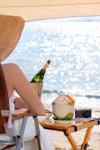 The Ritz-Carlton Sanya, Yalong Bay في سانيا: امرأة تجلس على كرسي على طاولة مع زجاجة من الشمبانيا