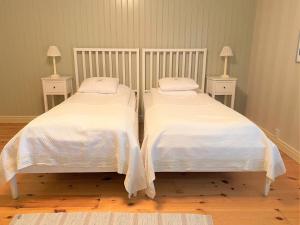 2 camas con mantas blancas y almohadas en una habitación en Stiftsgården Konferens & Hotell en Skellefteå