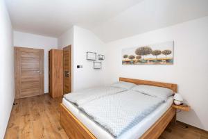 a white bedroom with a bed and a wooden floor at Nevinný sklep in Znojmo