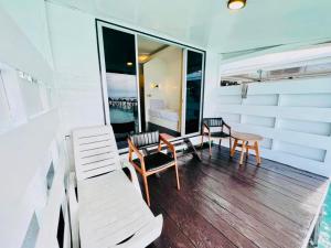 einen Balkon mit Stühlen, einem Tisch und einem Schlafzimmer in der Unterkunft Maglami-lami Water House in Semporna