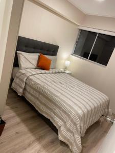 1 dormitorio con 1 cama grande con almohada naranja en Departamento de estreno en Zona exclusiva de Surco, en Lima