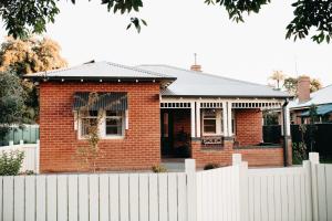 a red brick house with a white fence at The Settler - Boutique cottage in Dubbo
