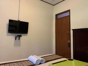 a room with a bed with a television on the wall at Urbanview Sasono Putro Condoongcatur by RedDoorz in Yogyakarta