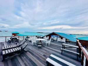 a wooden deck with tables and chairs on the water at Maglami-lami Water House in Semporna