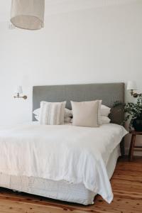 uma cama branca com lençóis e almofadas brancos em The Settler - Boutique cottage em Dubbo