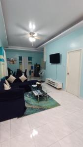 sala de estar con sofá negro y TV en Jens Samal Vacation Rental - Centrally Located - Fully Furnished 2br WIFI en Babak