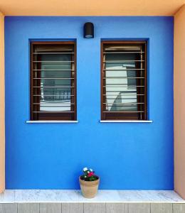a blue wall with two windows and a flower pot at Melia Villas in Ierissos