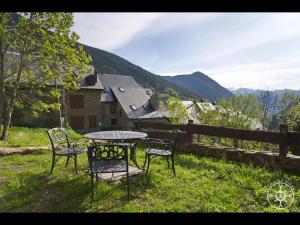 a table and chairs sitting in the grass near a fence at CASA CORILHA de Alma de Nieve in Salardú