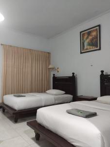 a hotel room with three beds and a window at Hotel Lestari in Gilimanuk