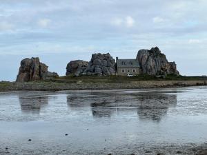 Una isla con una casa sobre algunas rocas en Gites le Rucher de Kerillis, en Plouguiel
