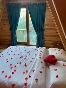 a bed with red roses on it with a window at Vaveyladağevleri in Çamlıhemşin
