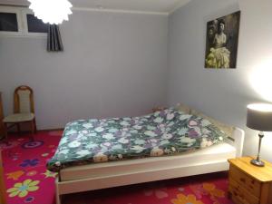 1 dormitorio con 1 cama con manta de flores en Biały Domek, noclegi Gołdap, en Gołdap
