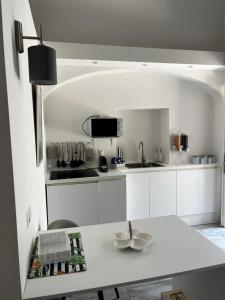 eine Küche mit weißen Schränken und einem weißen Tisch in der Unterkunft Soggiorno tra storia e design - la Domus in Ercolano
