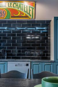 a kitchen with blue cabinets and a black brick wall at Apartament Pasaż in Giżycko