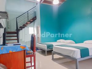 two beds in a room with a blue wall at Syariah Safar Guest House Mitra RedDoorz in Cijoho