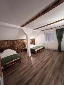 1 dormitorio con 2 camas y suelo de madera en Barlogul din Vidraru, en Curtea de Argeş