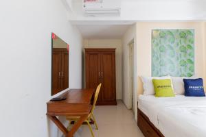 a bedroom with a bed and a desk and a bed and a table at Urbanview Erga Family Residence Syariah Surabaya in Surabaya