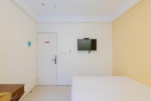 um quarto branco com uma cama e uma porta em Urbanview Erga Family Residence Syariah Surabaya em Surabaia
