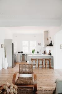 a white kitchen with a rattan chair and a table at The Settler - Boutique cottage in Dubbo
