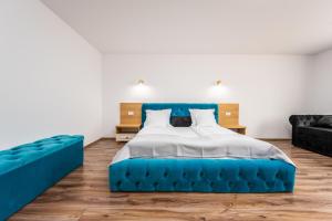 a bedroom with a blue bed and a blue couch at Ellys Residence in Voroneţ